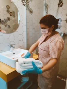 een vrouw met een gezichtsmasker en handschoenen met een stapel handdoeken bij Nayino Resort Hotel in Mamaia Nord – Năvodari