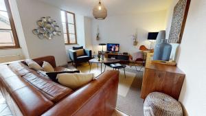 a living room with a brown leather couch and a tv at Sous les Tilleuls PARKING HYPERCENTRE 4-6 Personnes in Colmar