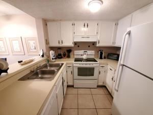 a kitchen with white cabinets and a sink and a refrigerator at St, Augustine Ocean And Racquet 2204 Condo in Saint Augustine