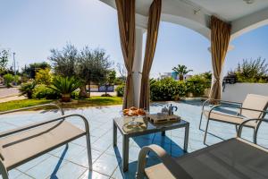a patio with chairs and a table and a pool at Callistos Apartment Pescoluse in Marina di Pescoluse