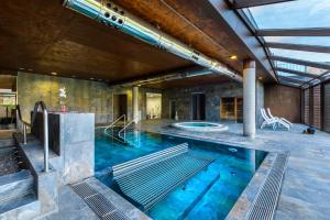 an indoor pool with blue water in a building at Hotel Spa Aguas de los Mallos in Murillo de Gállego