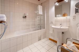 a white bathroom with a sink and a tub and a toilet at La Cour St-Fulrad - Les Suites in Saint-Hippolyte