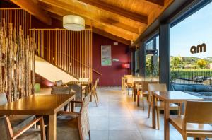 a restaurant with wooden tables and chairs and windows at Hotel Spa Aguas de los Mallos in Murillo de Gállego
