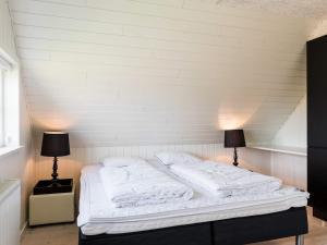 een wit bed in een kamer met 2 lampen bij Holiday home Blåvand CLXXXI in Blåvand