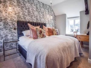 a bedroom with a large bed with floral wallpaper at Lovell Cottage in Witney