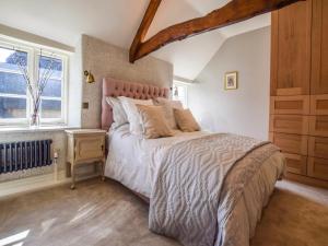 a bedroom with a large bed and a window at Lovell Cottage in Witney