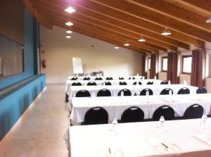 a conference room with white tables and black chairs at Hotel Spa Aguas de los Mallos in Murillo de Gállego +37 photos