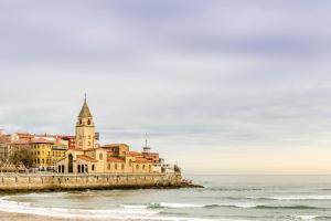 a building on the beach next to the ocean at Hotel Alcomar in Gijón