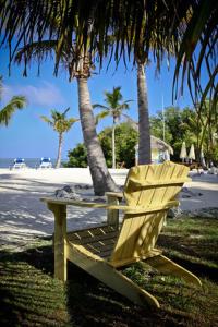una silla amarilla y una mesa en una playa con palmeras en Coconut Cove Resort & Marina, en Islamorada