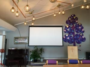 a blank screen on the wall of a room with chairs at Innvik Fjordhotell in Innvik