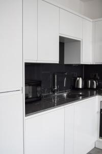 Morland Apartments - Hornchurch في Hornchurch: مطبخ أبيض مع دواليب بيضاء ومغسلة