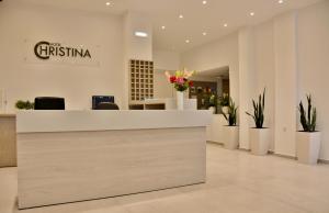 a lobby with a reception desk with flowers and plants at Christina Hotel in Adelianos Kampos