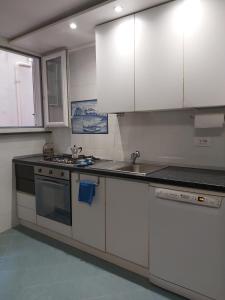 kuchnia z białymi szafkami, zlewem i kuchenką w obiekcie Casa Vacanze Aenaria-Ristrutturato 2024 w mieście Ischia