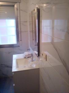 a white bathroom with a sink and a mirror at Casa La Torre in Isla de Arosa