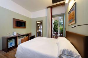 a bedroom with a white bed and a television at Best Western Hotel Rivoli in Rome