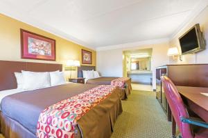 a hotel room with two beds and a desk at Days Inn by Wyndham Gainesville in Gainesville