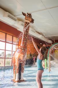 a girl playing with a giraffe in a swimming pool at Chessington Hotel in Chessington