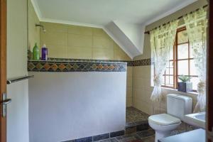 a bathroom with a toilet and a sink and a window at 41 Ridge- self catering cottages in Midrand
