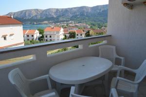 d'une table et de chaises blanches sur un balcon avec vue. dans l'établissement Apartments Leticia, à Baška