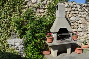 eine Steinmauer mit einem Außenofen mit Topfpflanzen in der Unterkunft Apartments Leticia in Baška