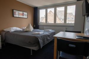 1 dormitorio con cama, escritorio y ventana en B&B De Hofnar Maastricht, en Maastricht