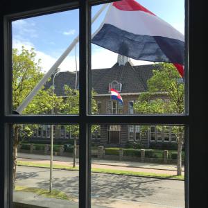 una finestra con una bandiera di fronte a un edificio di B&B Logeren bij Lies a Harderwijk