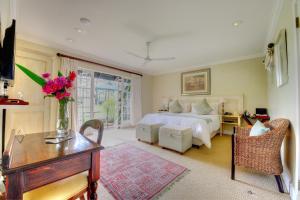 ein Schlafzimmer mit einem Bett und einem Tisch mit Blumen darauf in der Unterkunft Moorcroft Manor Boutique Country Hotel in Himeville