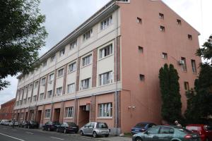 a large brick building with cars parked in front of it at Studio Cozy in Timişoara