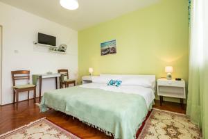 1 dormitorio con cama, mesa y TV en Muzic Budget Double Room, en Mali Lošinj