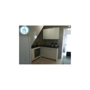 uma cozinha com armários brancos e um frigorífico em Casa da Avó Lucinda na Nazaré