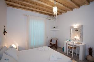 a white bedroom with a bed and a desk at Villa Meliti in Platis Gialos