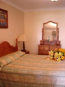 a bedroom with a bed with a dresser and a mirror at AbbeyCourt Kenmare Kerry in Kenmare