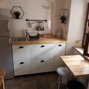 a kitchen with white cabinets and a sink and a table at Come to M2 in Zagreb