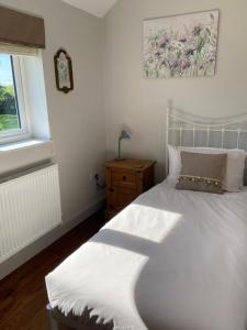 a bedroom with a white bed and a window at Lagard Stables in Whitley