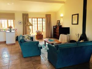 uma sala de estar com dois sofás azuis e uma mesa em Beverley Country Cottages em Dargle