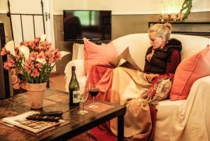 Beverley Country Cottages في Dargle: امرأة تجلس على أريكة مع زجاجة من النبيذ