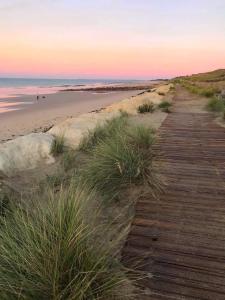 a boardwalk leading to the beach at sunset at Maison Amande in La Flotte