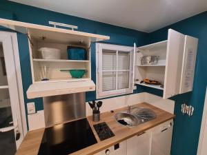 una cocina con armarios blancos y fregadero en Maison 2 Chambres Parking Linge de lit fourni, en Les Sables-dʼOlonne