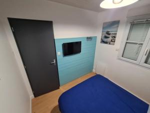 Pokój z niebieskimi drzwiami i telewizorem w obiekcie Maison 2 Chambres Parking Linge de lit fourni w mieście Les Sables-dʼOlonne