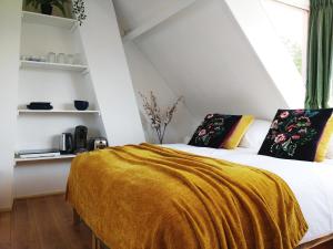 a bedroom with a bed with a yellow blanket at Appartementen Dorp & Duin in Egmond aan Zee