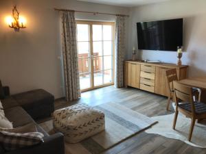 a living room with a couch and a tv and a table at Platzhirsch in Haus im Ennstal