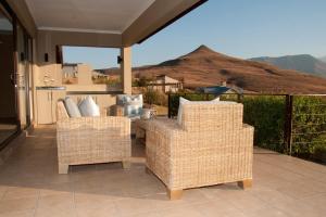 a patio with wicker chairs and a view of a mountain at Cathkin Haven in Champagne Valley