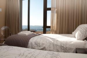2 camas en una habitación con ventana grande en Cathkin Haven, en Champagne Valley