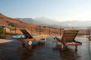 una terraza con 2 sillas y una piscina en Cathkin Haven, en Champagne Valley