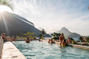 a group of people in a swimming pool with mountains in the background at Frendz Hostel El Nido in El Nido