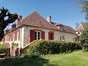 une ancienne maison blanche avec des portes rouges et une haie dans l'établissement Les Indrins, à Marzy