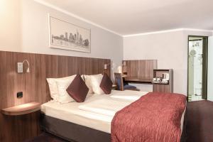 um quarto de hotel com uma cama grande e um cobertor vermelho em Ramada by Wyndham Frankfurt Central Station em Frankfurt