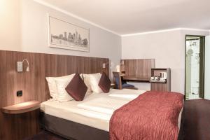 a hotel room with a large bed with a red blanket at Ramada by Wyndham Frankfurt Central Station in Frankfurt/Main