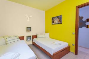 two beds in a room with yellow walls at Gerakina Skala Holiday Houses in Gerakini