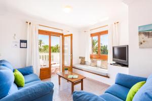 sala de estar con sofás azules y TV en Villa Olivera, en Son Bou